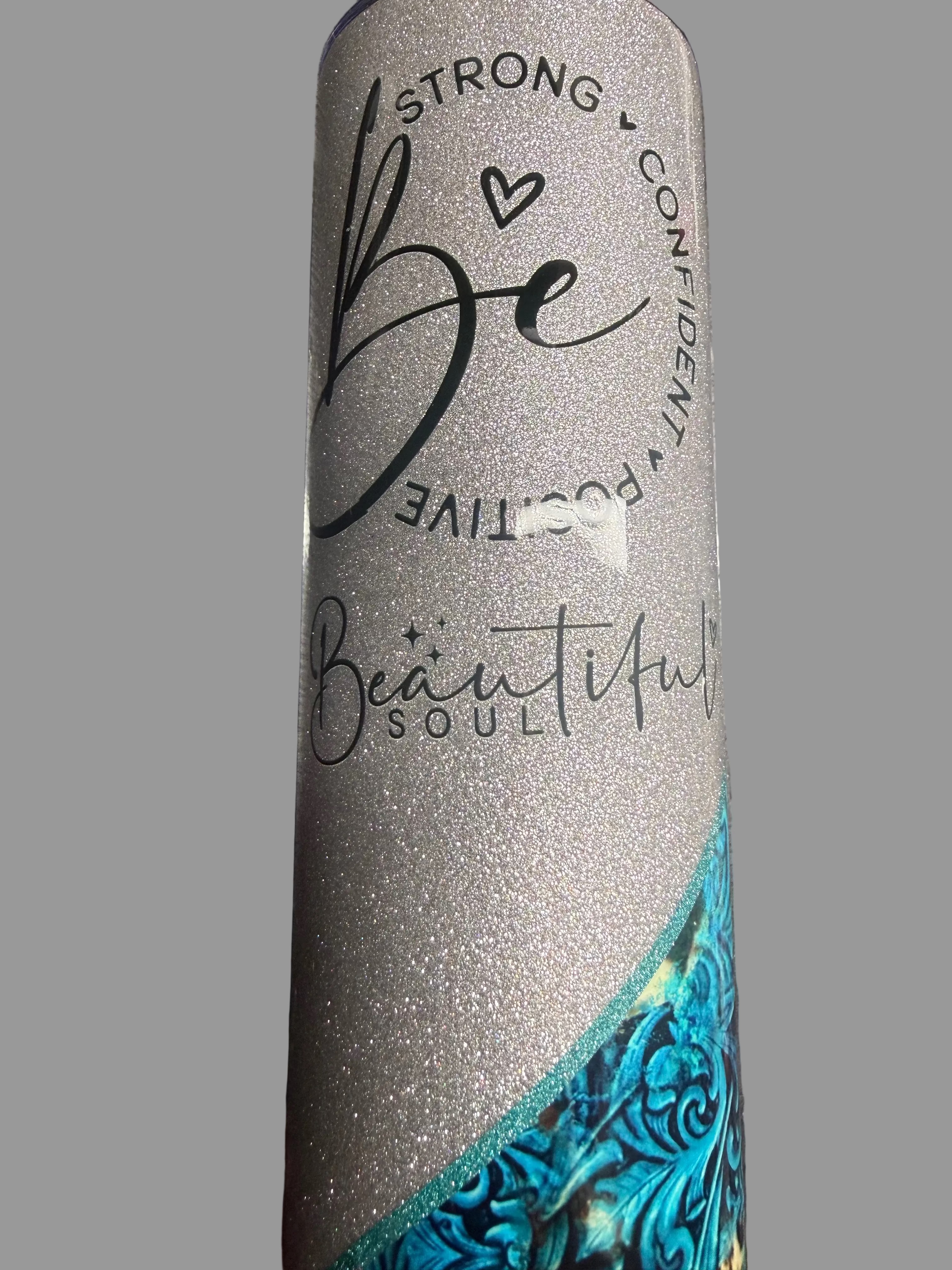 Silver tumbler with motivational text and blue accent on a metallic surface